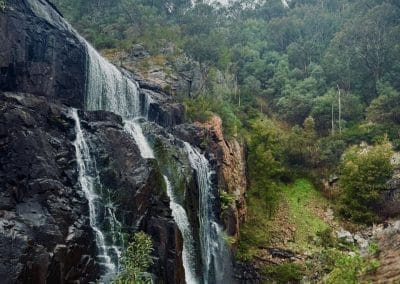 Waterfall cascading down a rocky cliff surrounded by lush green vegetation