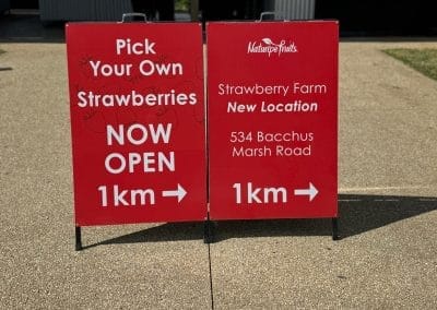 Red signs showing directions to a strawberry farm