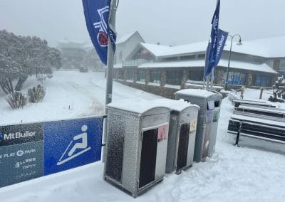 Snow-covered trash cans and signs at Mt Buller ski resort.