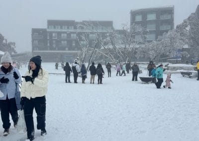 People gathered in a snow-covered village square with buildings in the background.