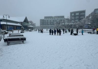 People gathered in a snow-covered village square with buildings in the background.