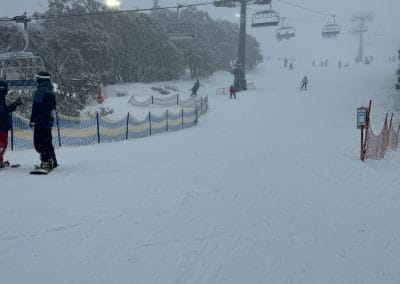 Skiers on a snowy slope with chairlifts and fog.