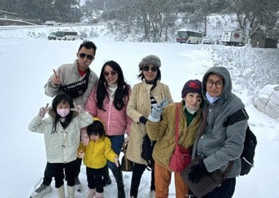 Seven people in winter clothes pose in the snow.